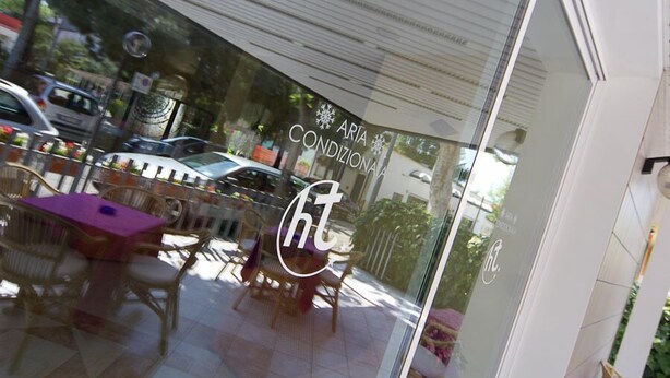 Un restaurante con terraza, fachada de vidrio y el nombre "ARTA CONDIZIONALE" a la vista.