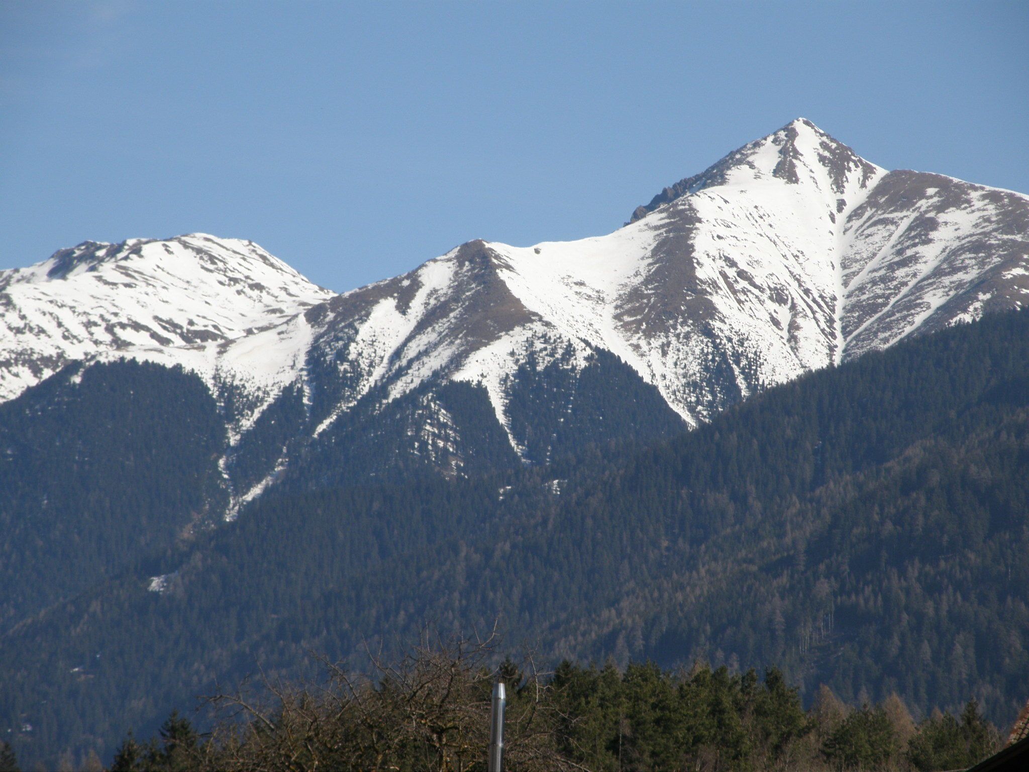 A mountain range with snow-capped peaks and dense forested valleys.
