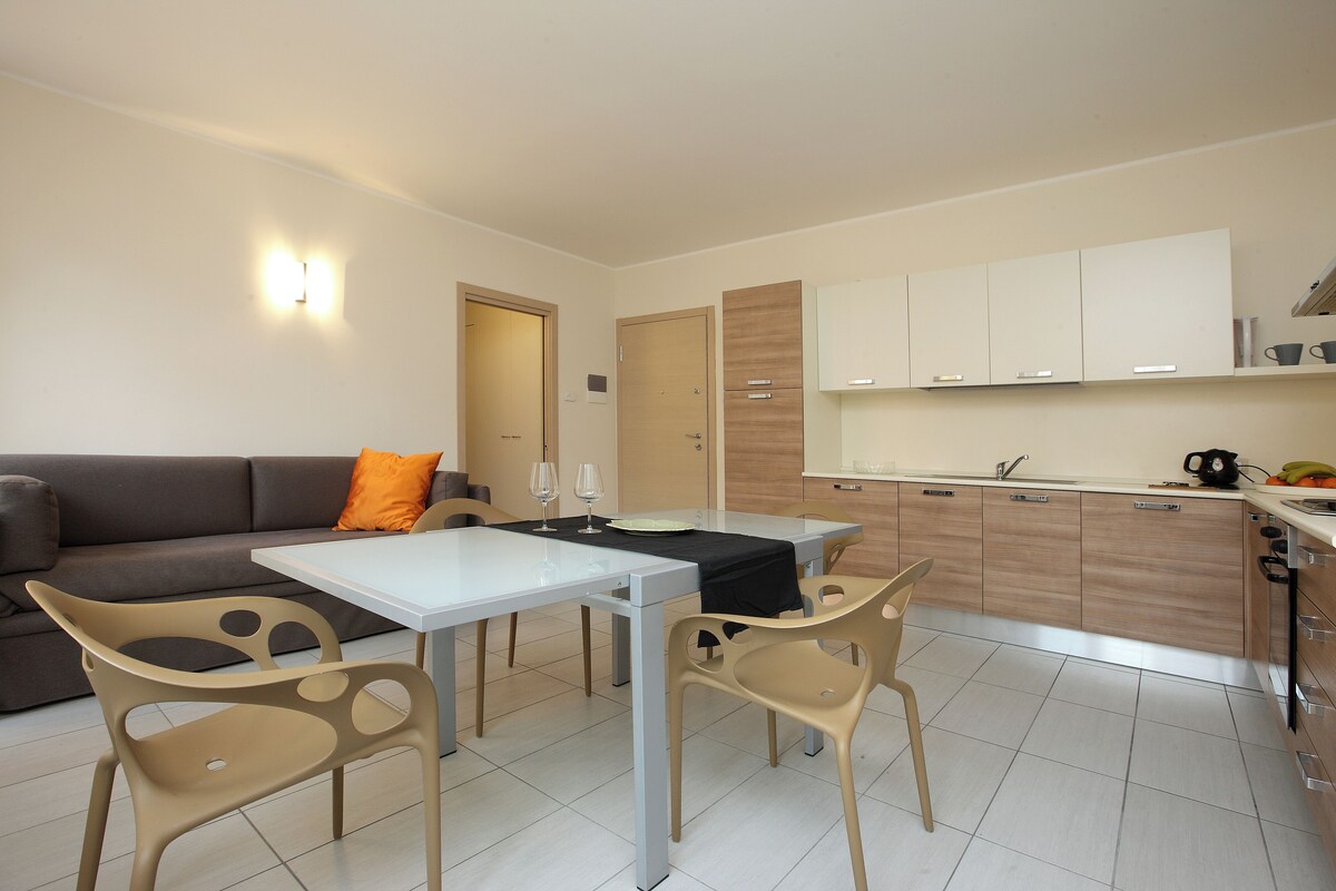 Un espacio habitable compacto con una mesa de comedor, sillas, sofá y kitchenette.