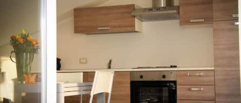 Una cocina moderna con armarios de madera, un horno de acero inoxidable y una silla blanca.