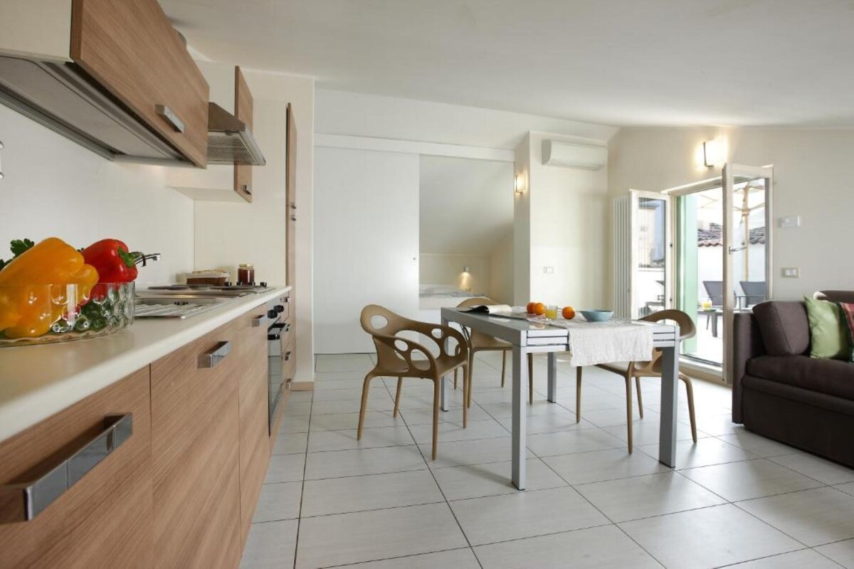 Una cocina moderna con armarios de madera, una mesa de comedor con sillas y vistas al área de estar.