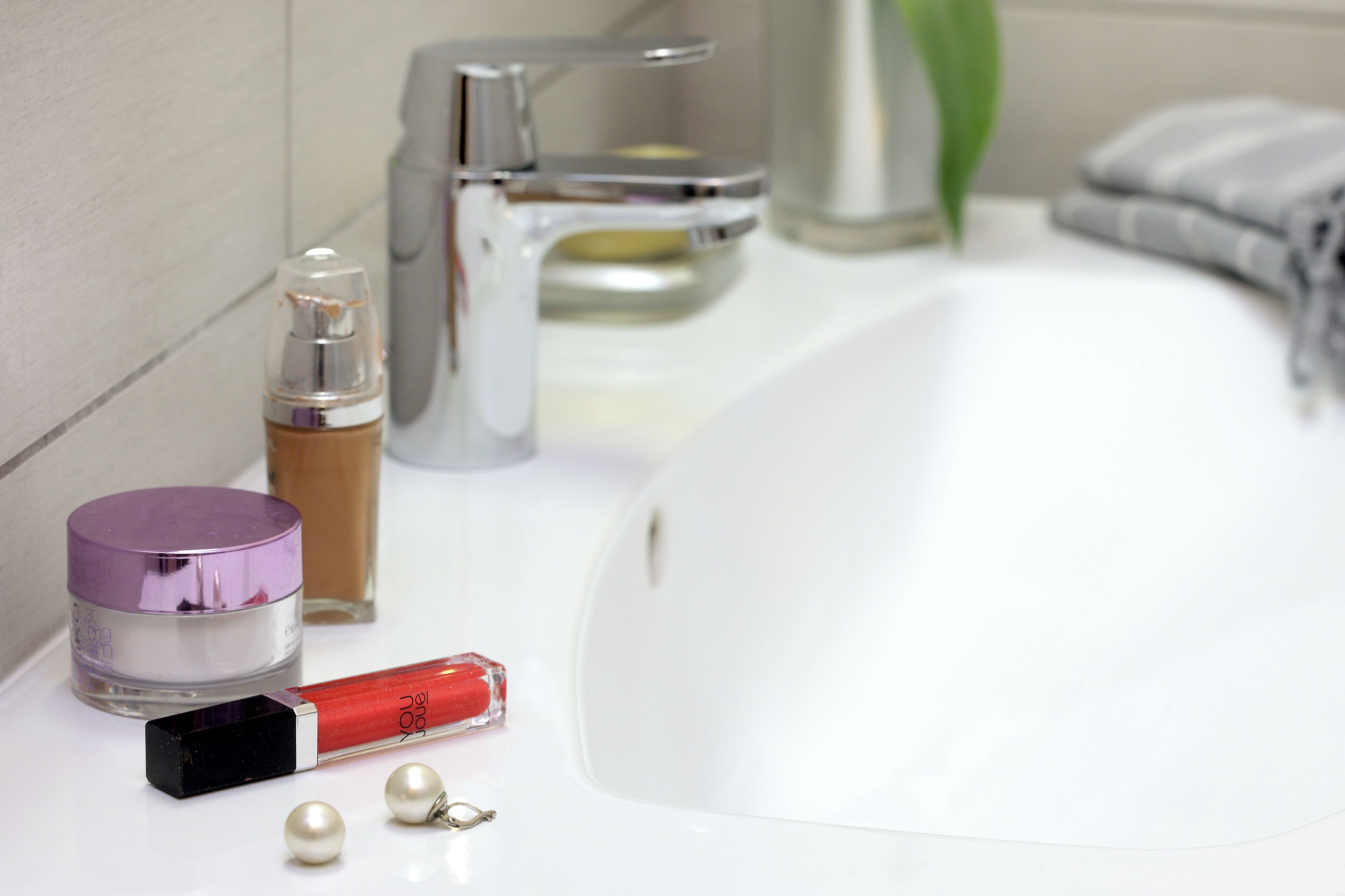 A bathroom sink with a mirror, a bottle of liquid soap, a razor, and a container of cream.