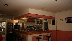 Un espace bar avec des tabourets, un comptoir et des étagères remplies de bouteilles.