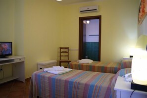A hotel room with two beds, a desk with a television, a chair, and a bathroom visible through a door. - Hotel Oltremare (Fiumicino)
