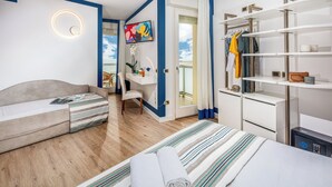 Et moderne hotelværelse med seng, sofa, skrivebord med computer, fjernsyn og garderobeskab.