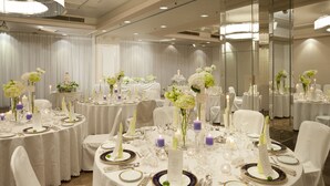 A banquet hall with round tables set for a formal event, featuring white tablecloths, floral centerpieces, and candle holders. - Chofu Creston Hotel (Chofu)