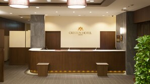 A reception desk with a logo, wooden paneling, and a plant. - Chofu Creston Hotel (Chofu)