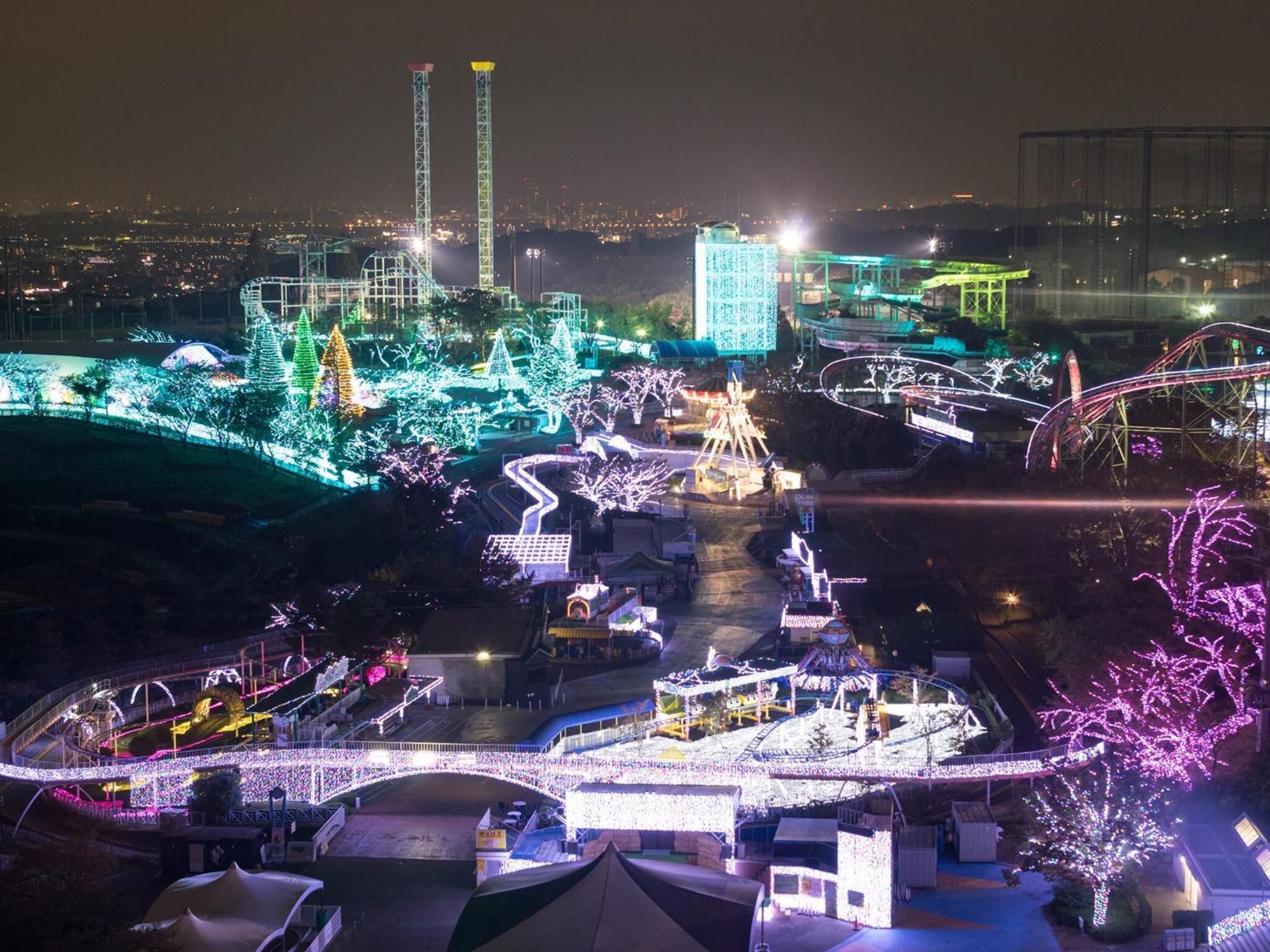 A brightly lit amusement park at night with various rides and attractions.