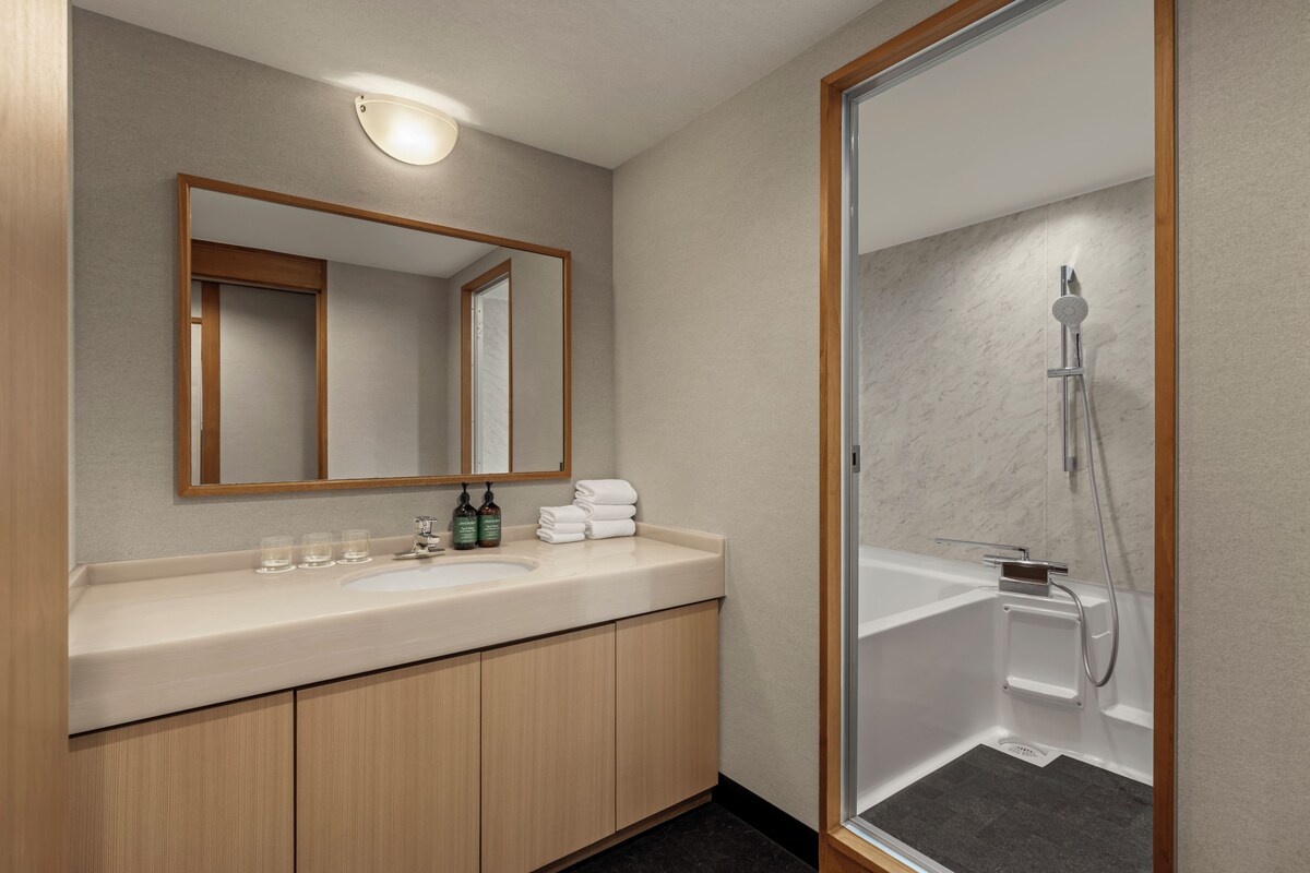 A bathroom with a sink, mirror, and shower.