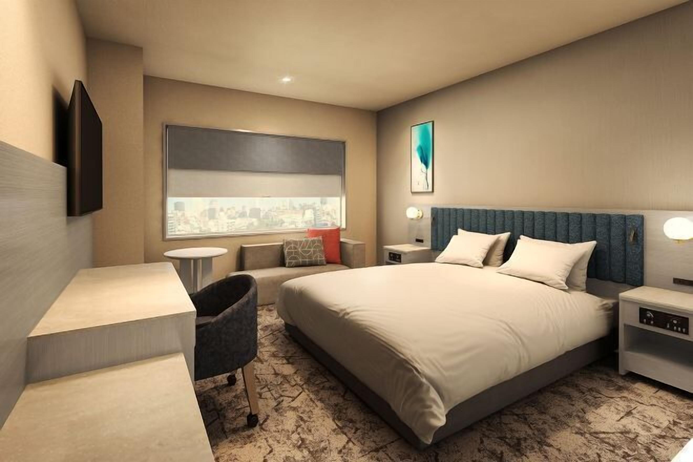 A hotel room with a bed, bedside tables, a desk, a chair, a window with a city view, and a painting on the wall.