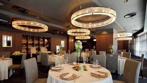 A restaurant with round tables, chairs, and chandeliers. - Crowne Plaza - ANA Hamamatsu by IHG (Hamamatsu)