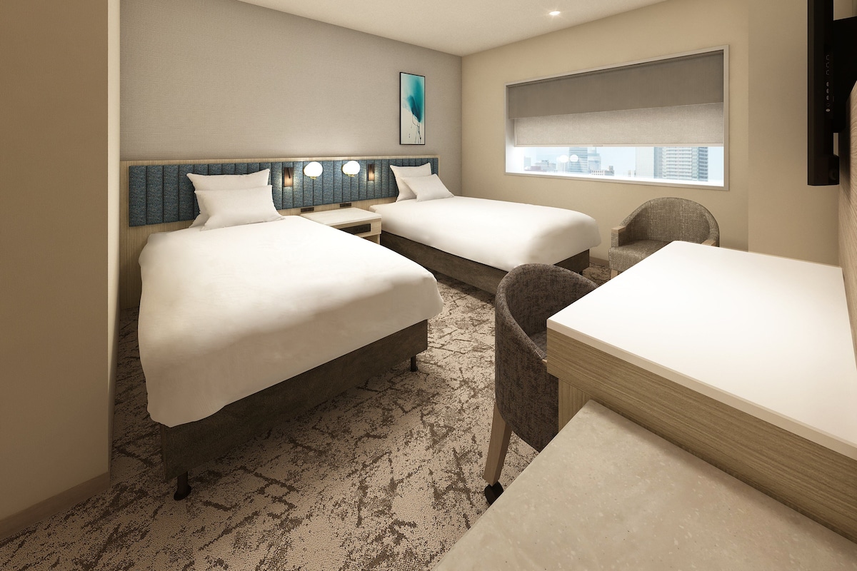 A hotel room with two beds, a desk, a chair, a city view, and a mounted TV.