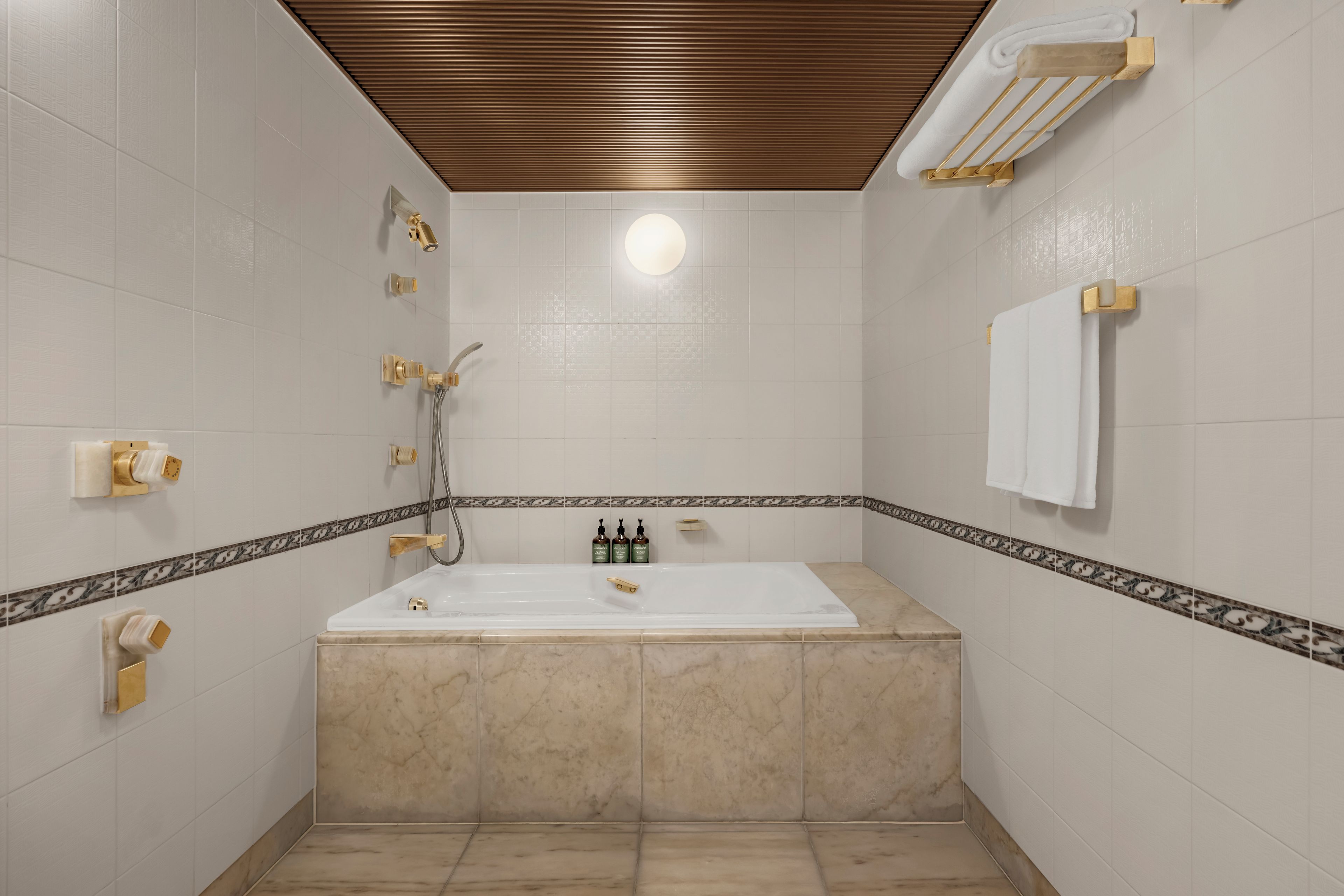 Un baño con bañera, ducha y toalleros.