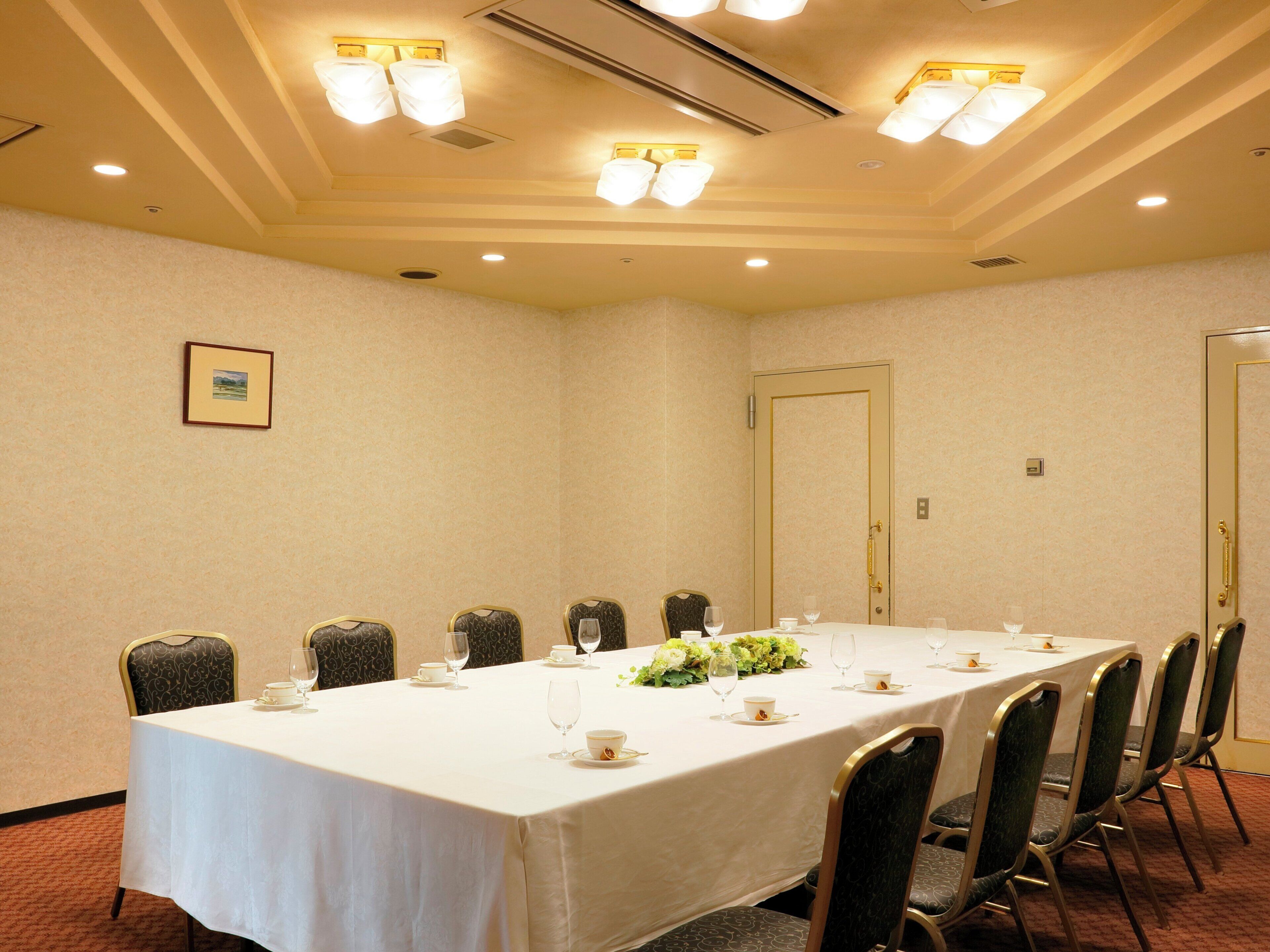 Une salle de conférence avec une longue table, des chaises et un tableau encadré accroché au mur.