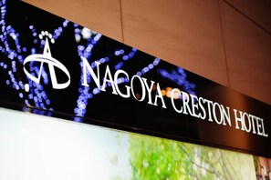 A hotel sign with the name "NAGOYA CRESTON HOTEL" and a logo.