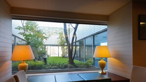 A modern hotel room with a large window, two lamps, a sofa, and a small table. - Nagoya Creston Hotel (Nagoya)
