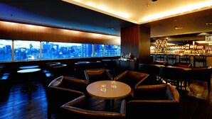 A bar area with a city view, leather seating, and a bar counter with bottles. - Nagoya Creston Hotel (Nagoya)