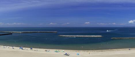 Una playa con vista despejada al océano, un muelle y un faro a lo lejos.