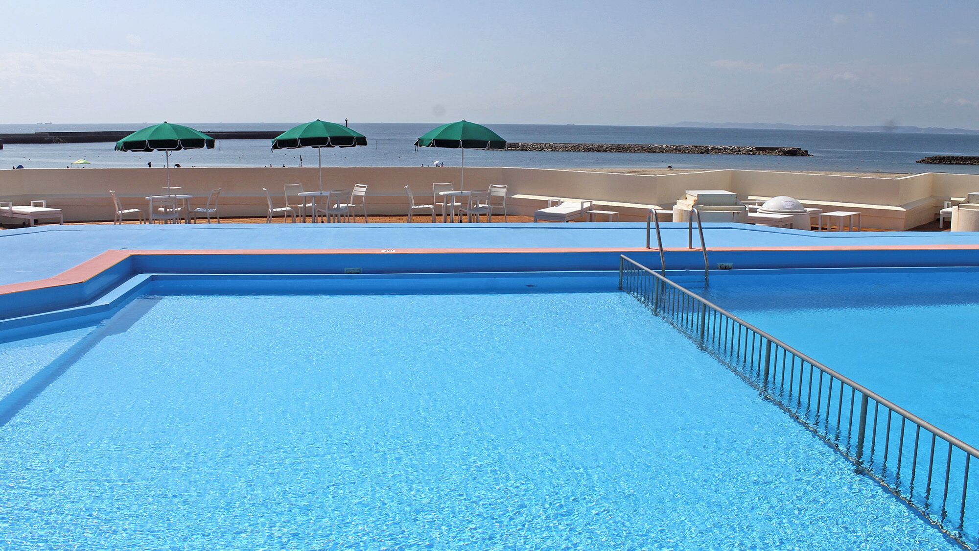 A swimming pool with a view of the beach and ocean.