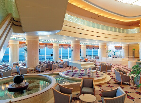 A spacious lobby with a central water feature, seating areas, and large windows offering ocean views. - Irago Resort & Convention Hotel (Tahara)