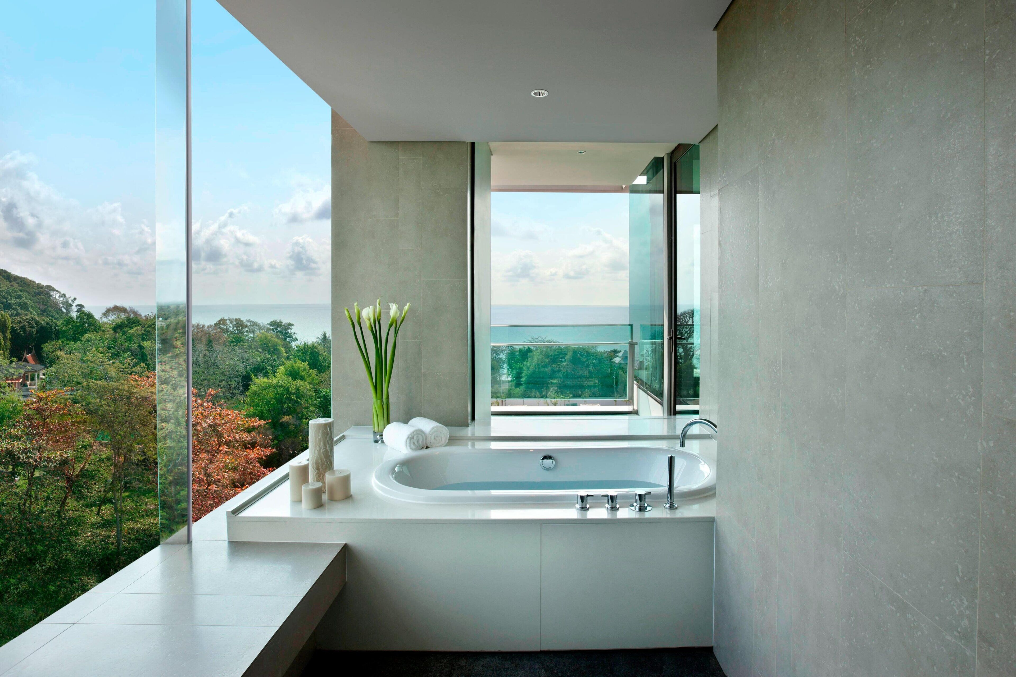 Un baño moderno con una bañera grande, un box de ducha de vidrio y vistas a un paisaje exuberante.