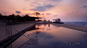 Un área de piscina tranquila con vista al atardecer, reflejando el cielo y la arquitectura circundante.