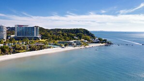 A coastal hotel with a beach view, multiple buildings, and a forested hill in the background. - Rayong Marriott Resort & Spa (Klaeng)
