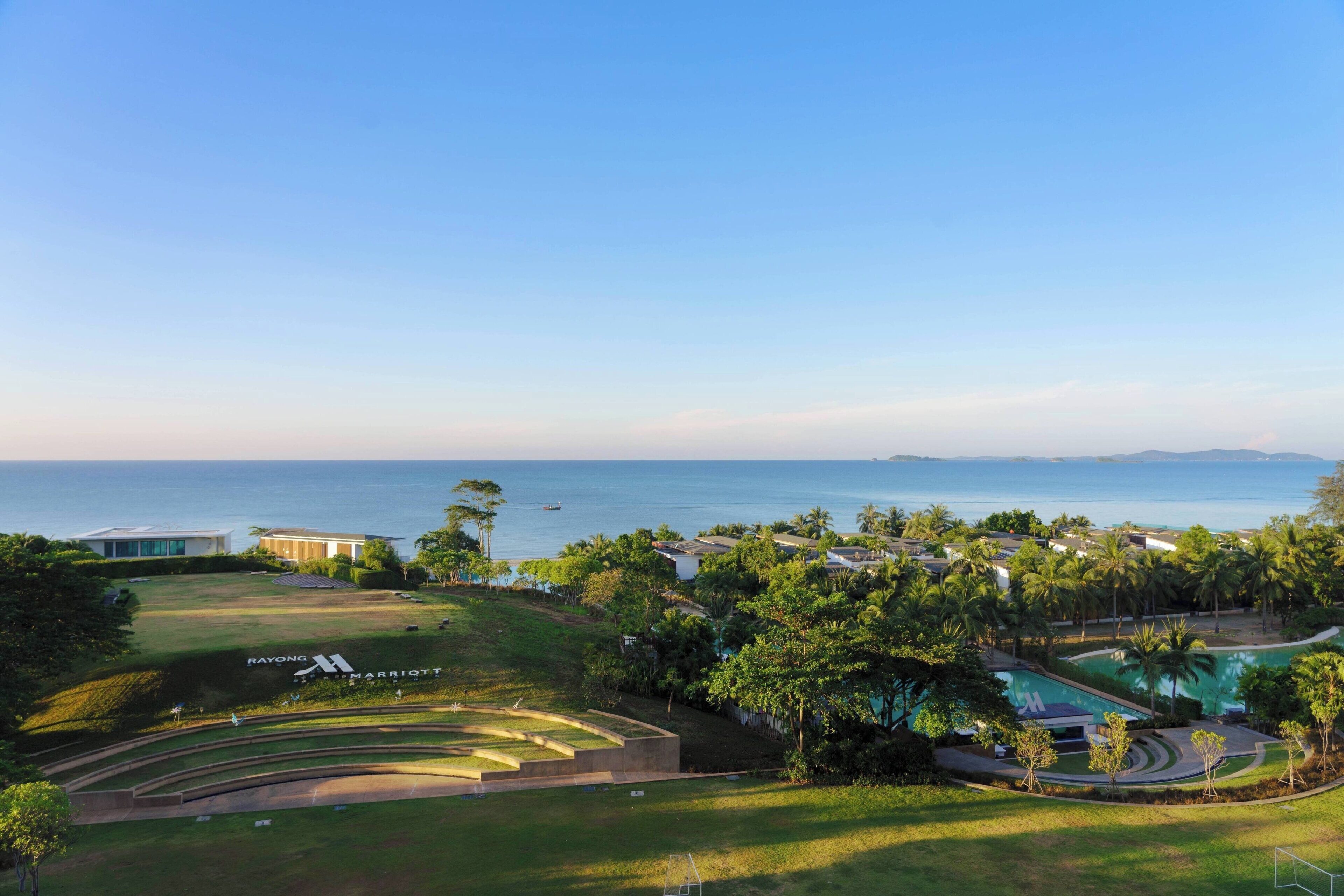 A golf course with a swimming pool, palm trees, and a view of the ocean.