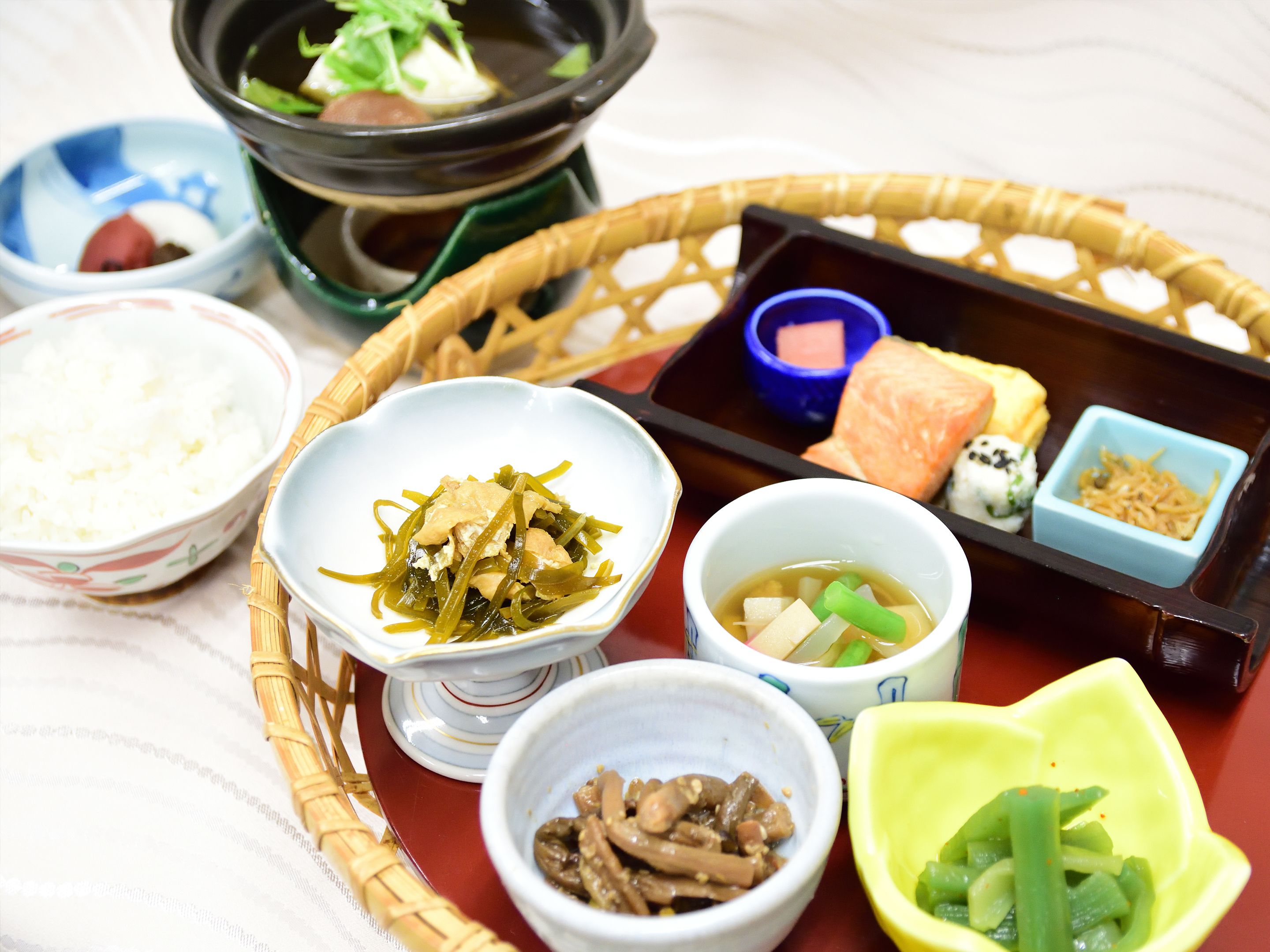 Une variété de plats, notamment du riz, des algues, du tofu et des légumes, servis dans une boîte à bento traditionnelle japonaise.