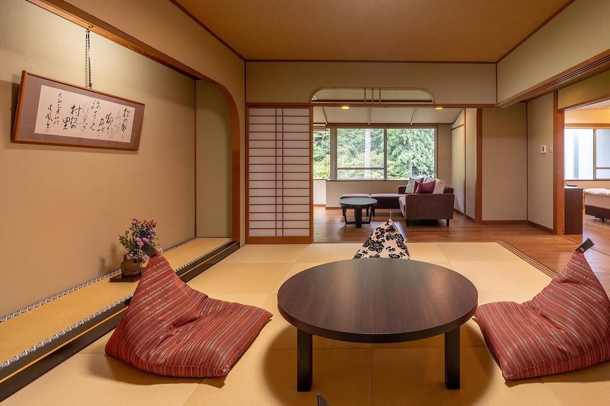 Una habitación japonesa tradicional con suelo de tatami, una mesa baja, cojines y puertas correderas.