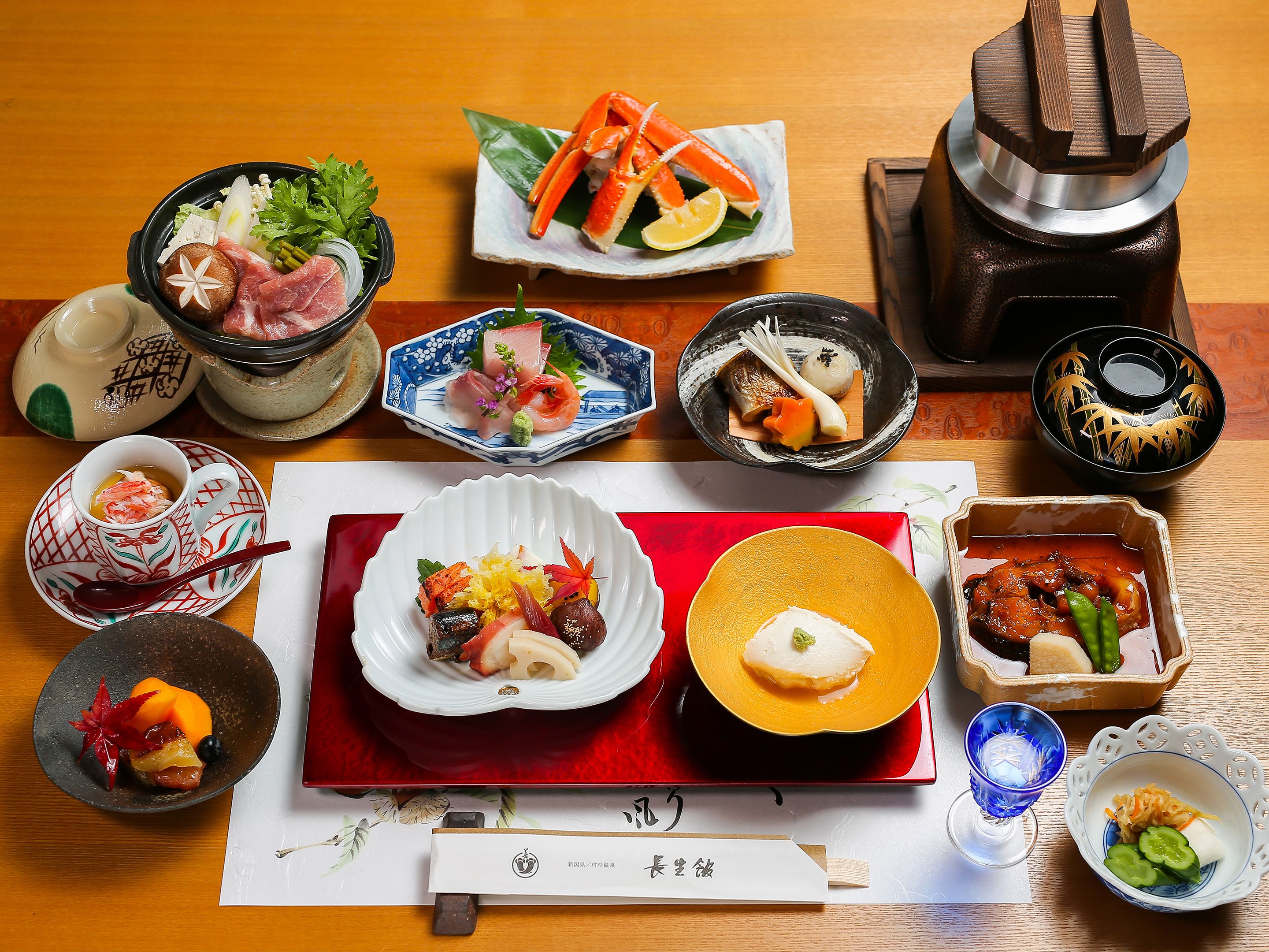 Variedad de platos japoneses dispuestos sobre una mesa de madera, incluyendo sushi, sashimi y otras exquisiteces.