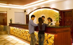 A reception area with a wooden reception desk, a whiteboard, and a patterned wall.
