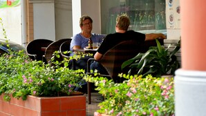 Two people seated at a table in an outdoor cafe area with potted plants and a brick wall. - Guangzhou Masia Hotel (Guangzhou)