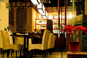 A restaurant interior with brick walls, wooden furniture, and a glass display case.