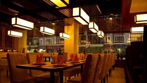 A restaurant with tables set for dining, featuring a traditional interior with hanging lanterns and a view of the street outside. - Guangzhou Masia Hotel (Guangzhou)