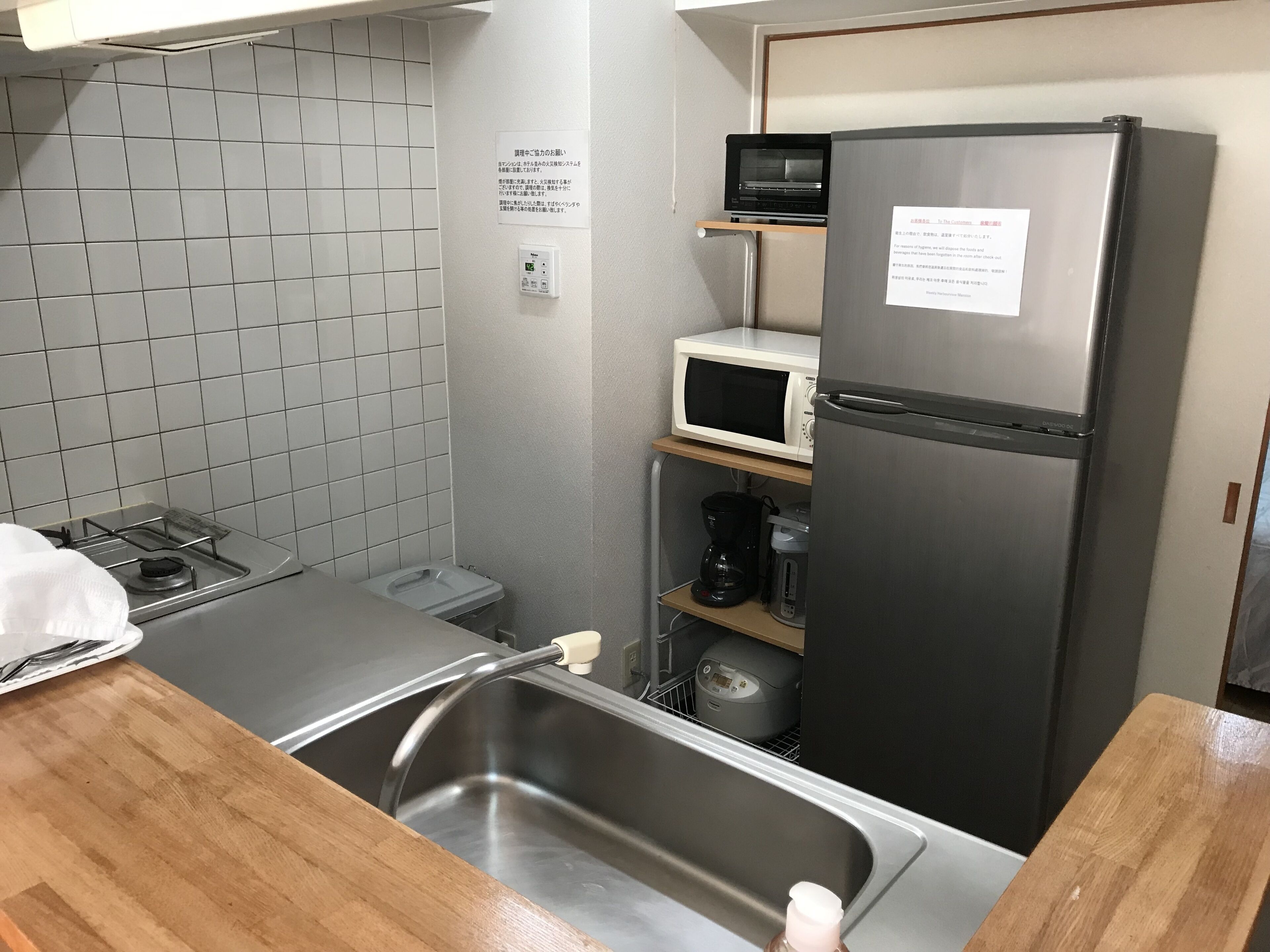 A compact kitchen with a gas stove, a sink, a microwave, and a refrigerator.