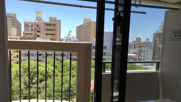 A balcony with a view of a cityscape, including buildings and greenery. - Weekly Harborview Mansion - Main Building (Naha)