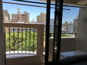 Un balcón con vistas a un paisaje urbano, incluyendo edificios y zonas verdes.