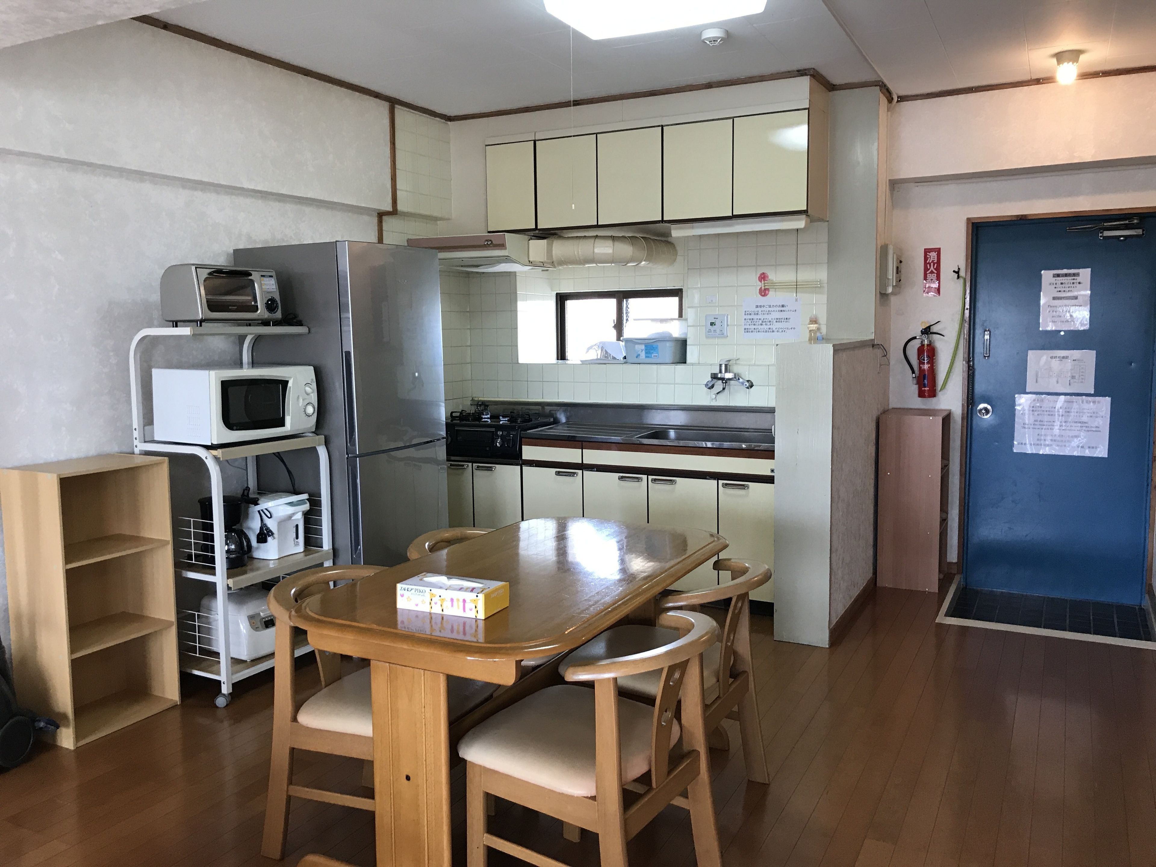 A compact kitchen with a dining table and chairs, a microwave, a refrigerator, and a stove.