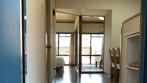 A hallway with a tiled floor leading to a room with a bed and a window. - Weekly Harborview Mansion - Main Building (Naha)
