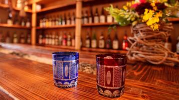 Two glasses on a wooden bar counter with a blurred background of shelves with bottles.