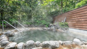 A hot spring surrounded by rocks and a wooden wall. - Hotel Kirishima Castle (Kirishima)