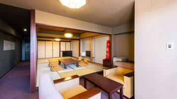 Una habitación tradicional japonesa con suelo de tatami, una mesa baja de madera, un sofá y un televisor.