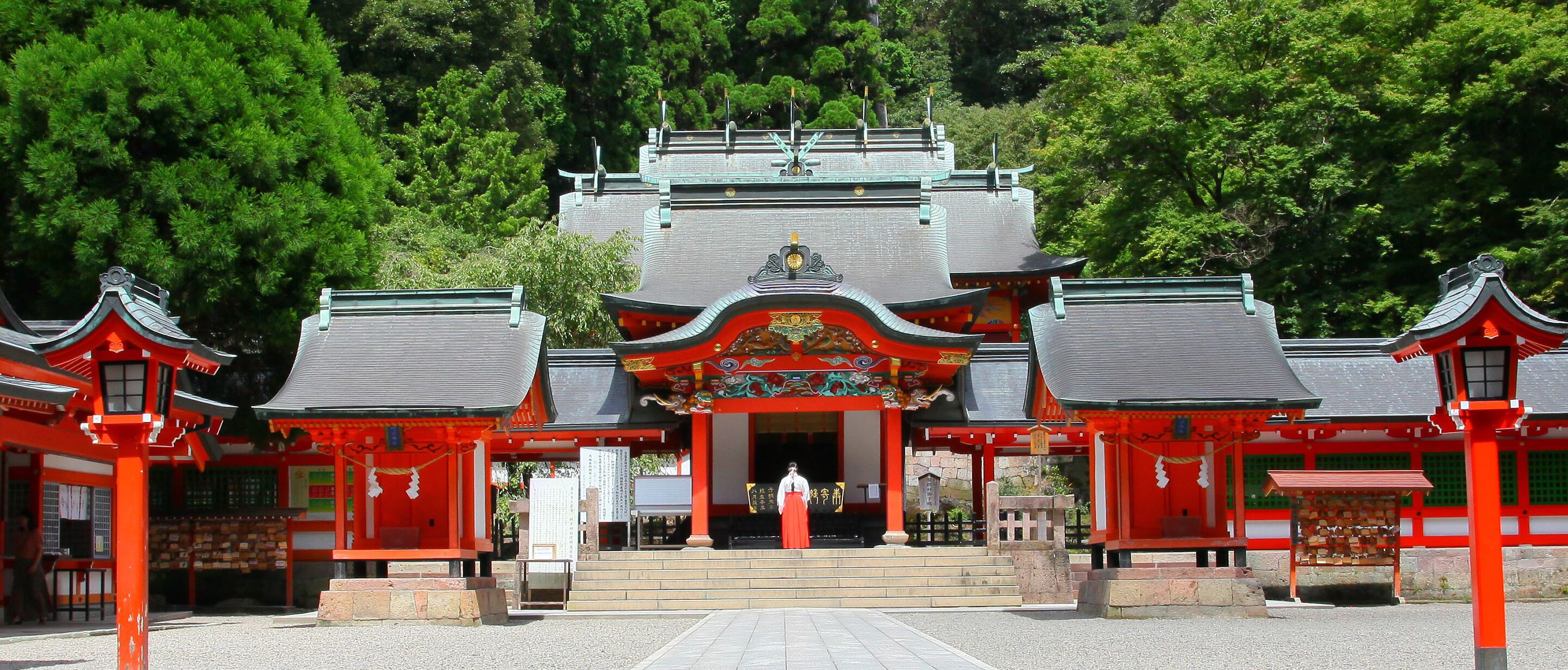 Un templo japonés tradicional con una entrada central, rodeado de torii rojos y una escalera que conduce al salón principal.