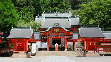 Un templo japonés tradicional con una entrada central, rodeado de torii rojos y una escalera que conduce al salón principal.