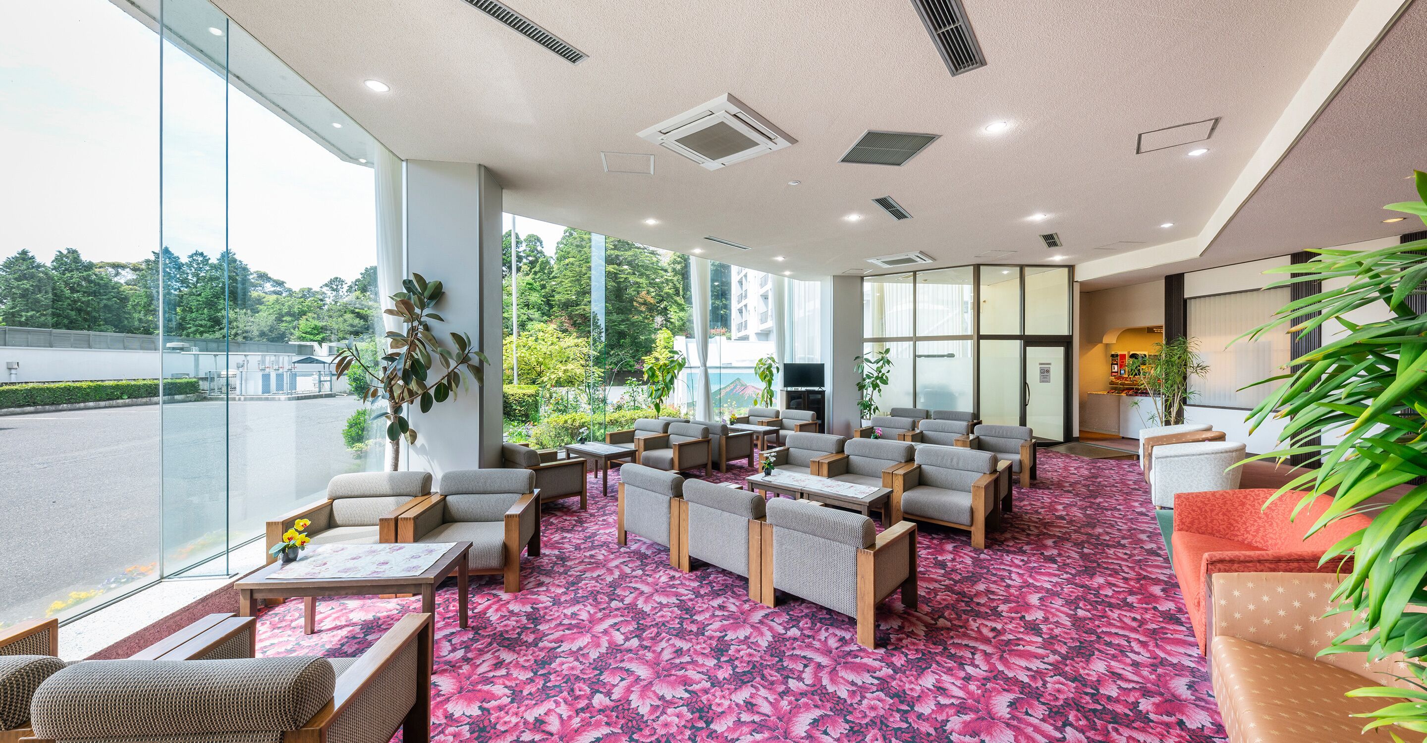A spacious indoor area with seating arrangements, large windows, and a view of the outdoors.