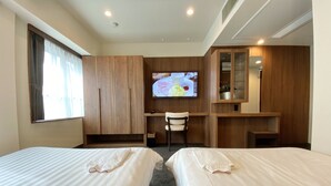 Habitación de hotel con dos camas, un escritorio, televisor y espejo.