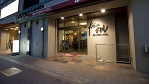 Exterior del Hotel Kadoya, con entrada despejada, recepción visible y un cartel.