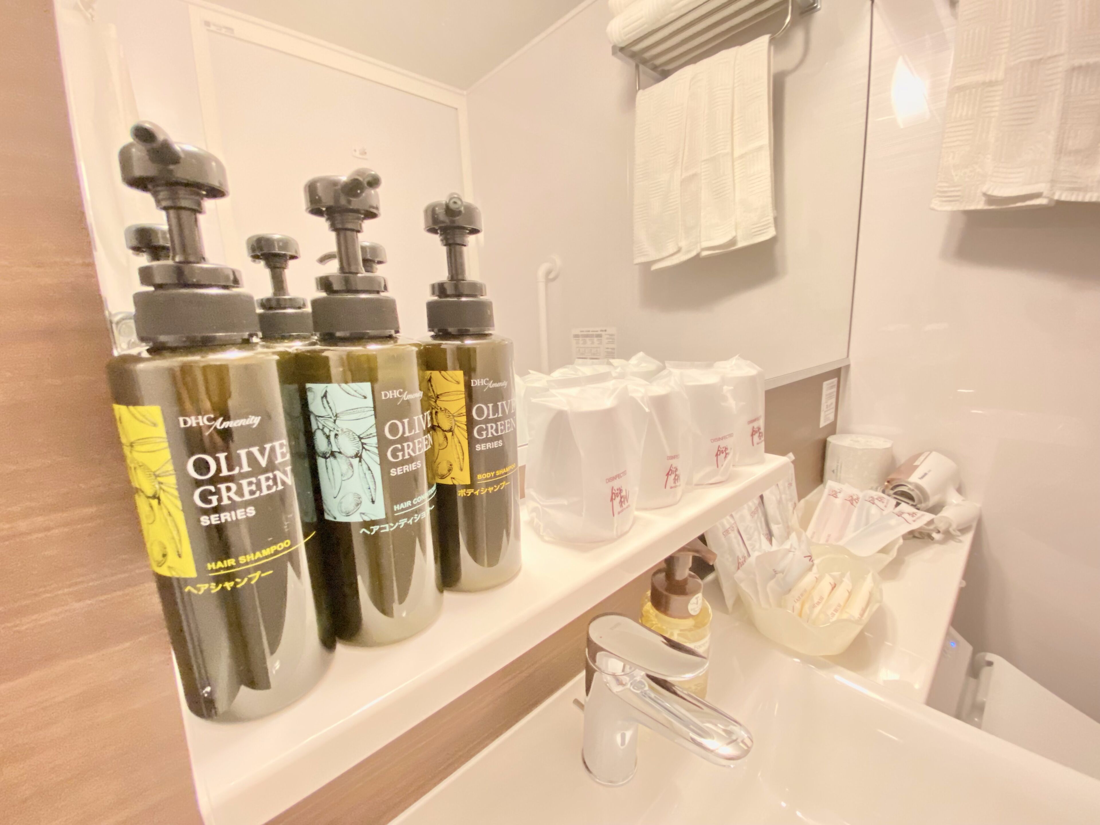 A bathroom with a shelf holding hair care products, a mirror, and a towel rack.