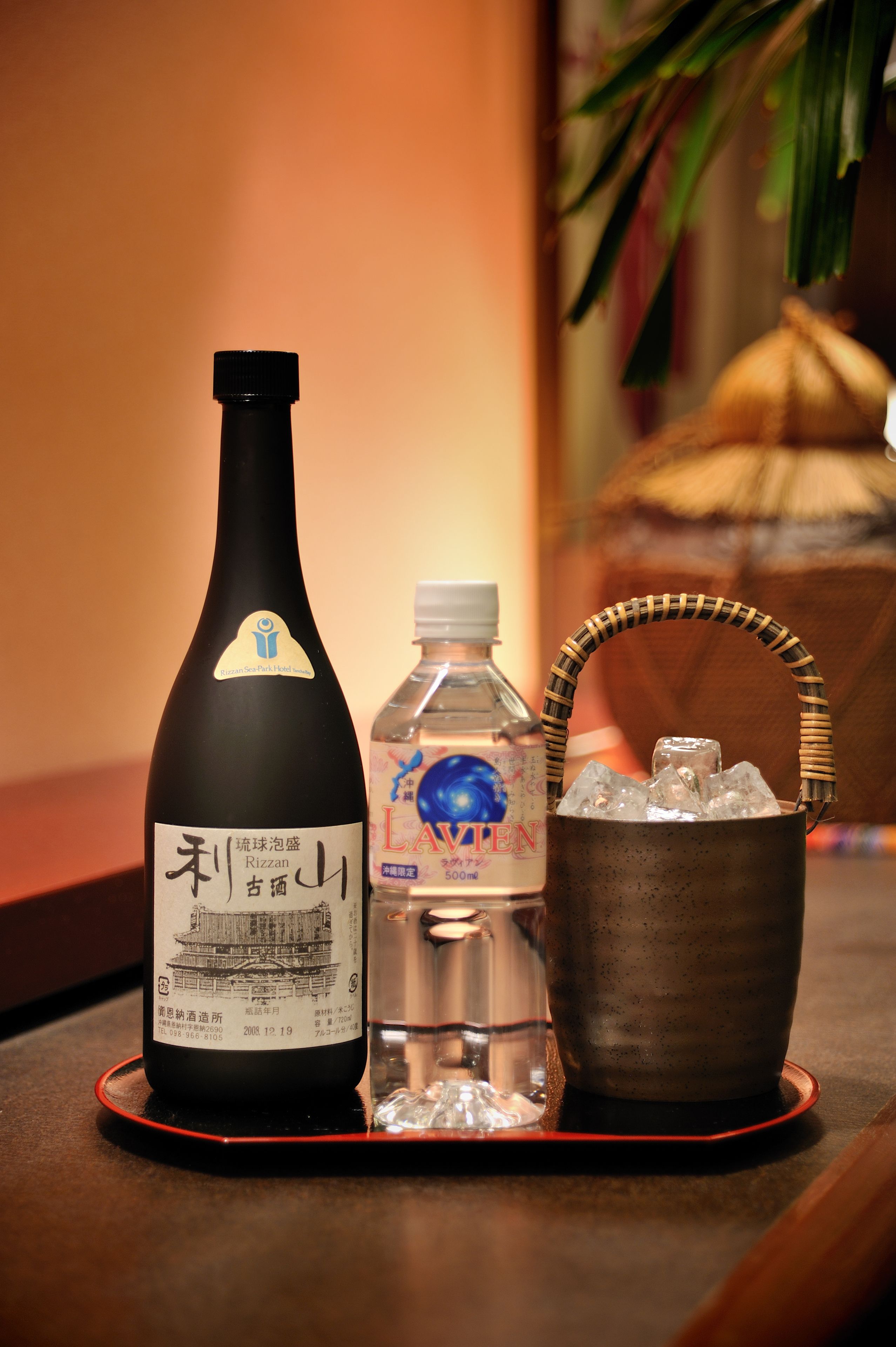 A bottle of sake, a bottle of water, and a metal bucket with ice on a tray.